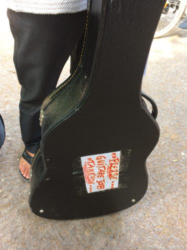 Dino's guitar case, with a sign reading "Please Guitare Job Tank You"